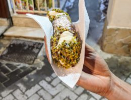 Syrakuzy - tradycyjne sycylijskie cannolo z ricottą maczane w kruszonych pistacjach
